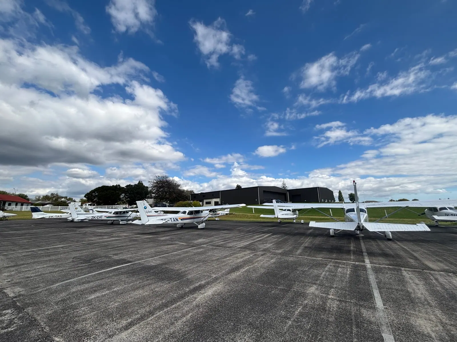 Training aircraft of a partner flight school lined up on the apron under a blue sky