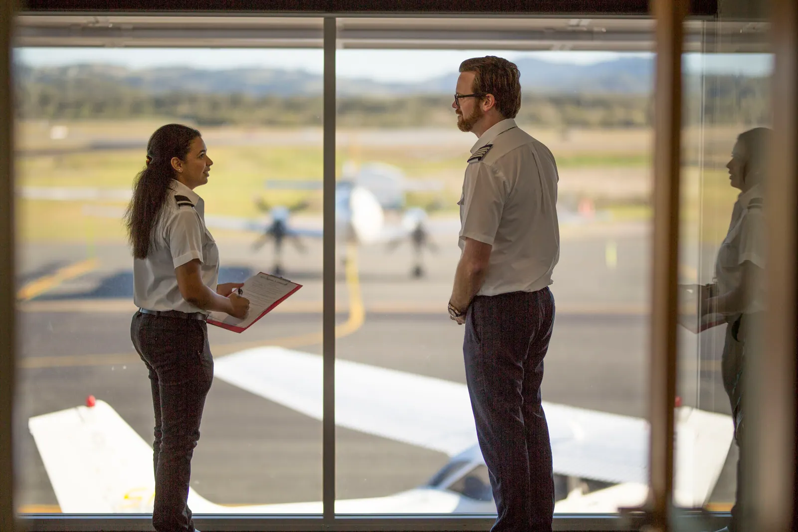 A flight instructor briefing a student beside a training aircraft